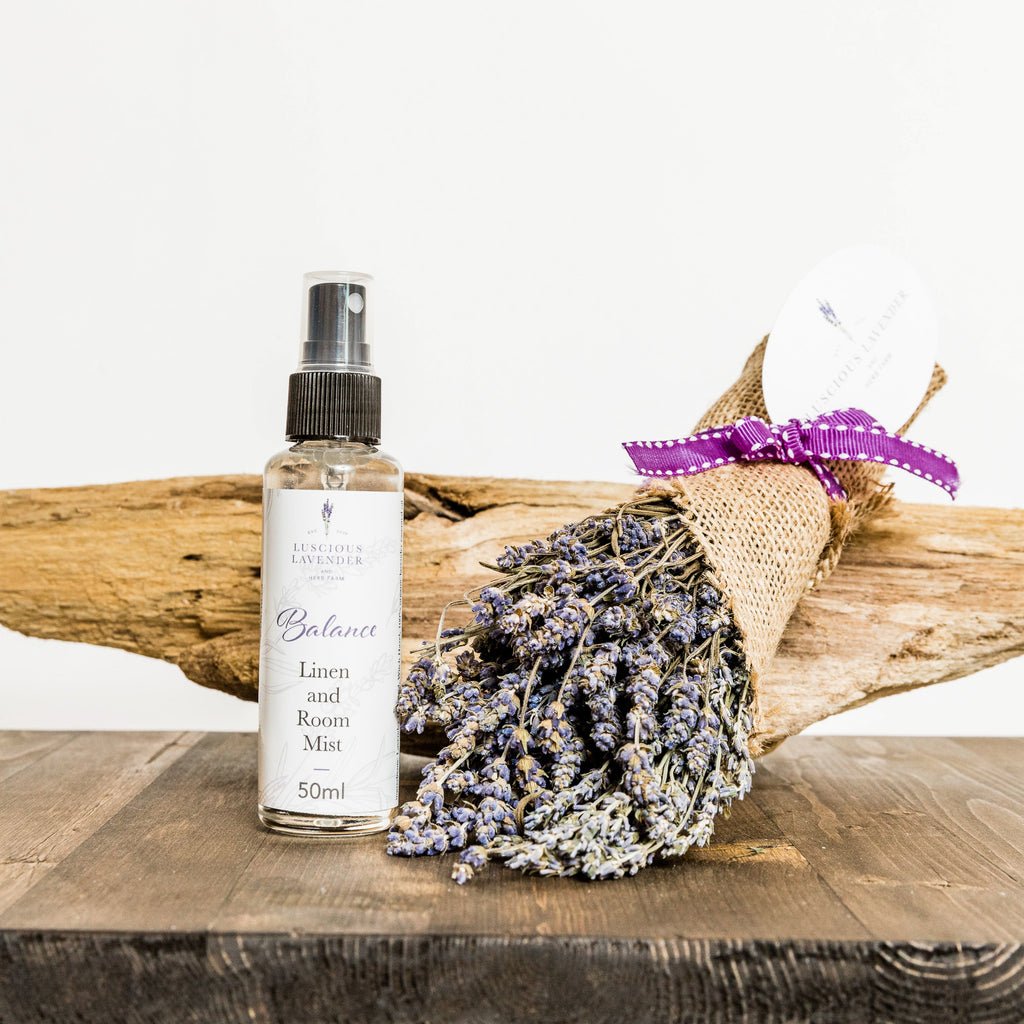 Balance linen room mist in clear bottle next to a bundle of fresh dried lavender